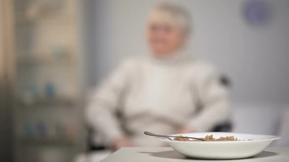 Sad Old Woman in Wheelchair Looking at Untasty Dinner in Medical Center, Sorrow