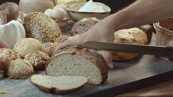 Hands Cutting the Baked Dutch Bread on the Table