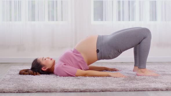 Pregnant Asian young woman breathing meditation with yoga Half Bridge pose