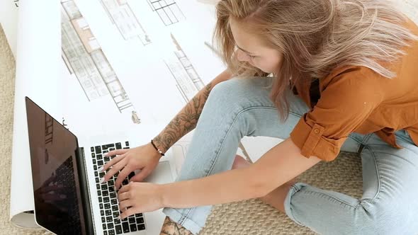 Girl with drawings of architectural project home and working with a laptop
