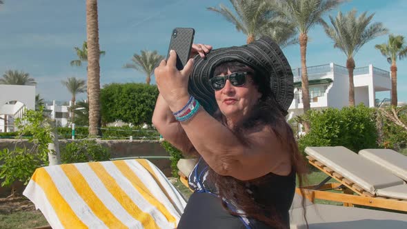 Caucasian Senior Female Elderly in Black Hat Talking on Video Call on a Smartphone