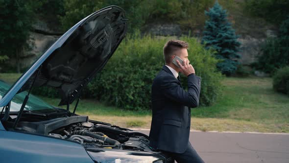 Man Talking on the Phone and Looking at the Car's Engine
