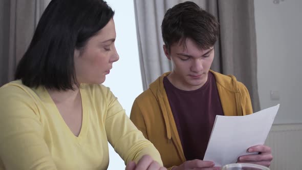 Close-up Side View of Young Caucasian Woman Drinking Tea As Getting Bad News From Teenage Son