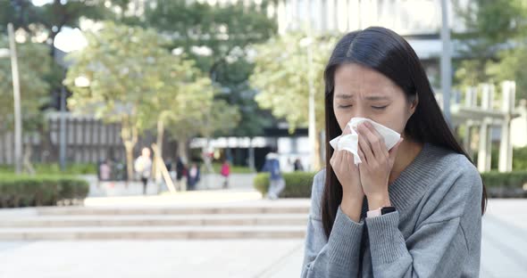 Woman sneezing at outdoor