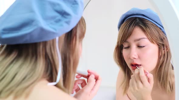 Beautiful young asian woman applying lipstick pink