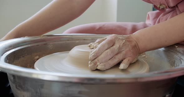 Female Potter Sitting and Makes a Cup on the Pottery Wheel. Woman Making Ceramic Item. Pottery