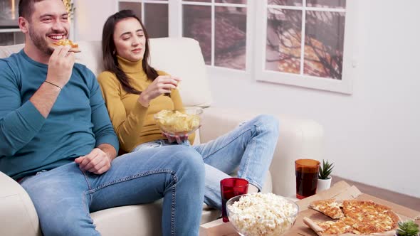 Caucasian Young Couple Sitting on Couch Eating Pizza