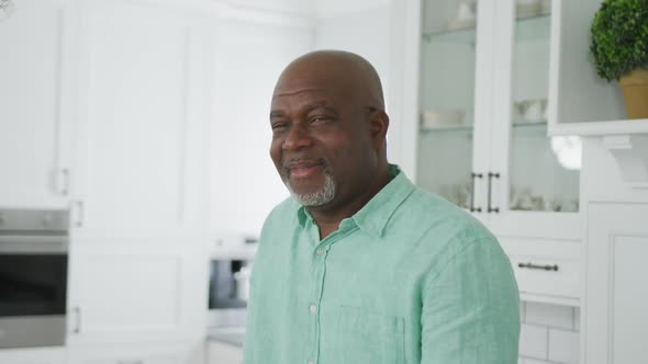 Portrait of smiling senior african american man looking at camera in kitchen