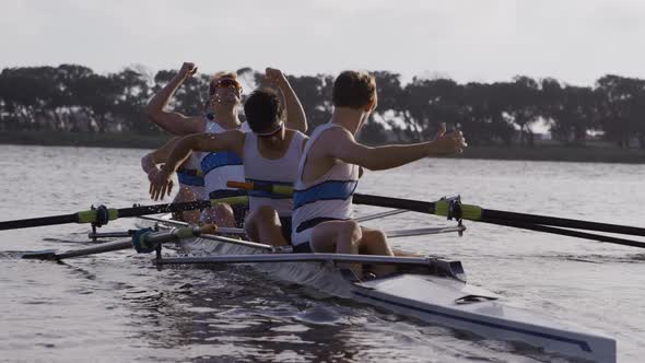 Front view of male rower team celebrating on the lake