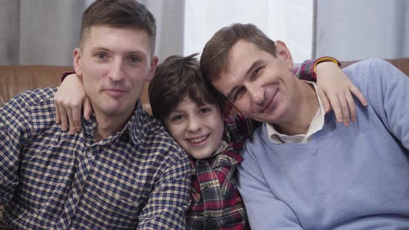 Close-up Portrait of Three Caucasian Men of Different Ages Looking at Camera and Smiling