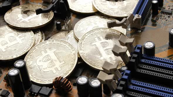 Golden coins with bitcoin symbol on electronic circuits in a computer mainboard.