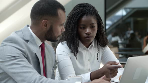 Focused Young Business People Pointing at Laptop