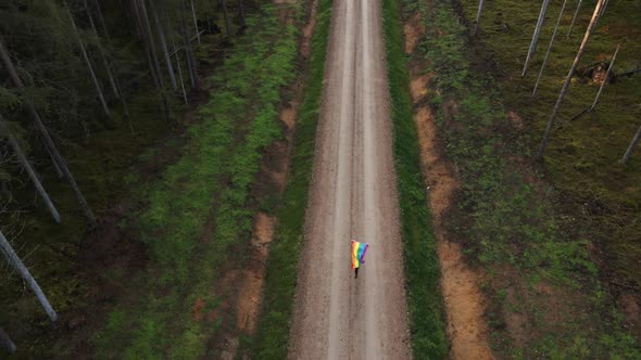 Top Aerial View: Lesbian Woman Running with Waving Huge Rainbow LGBT Flag