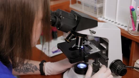 A Woman in a Lab Coat is Getting Ready to Start a Microscope Research in a Lab