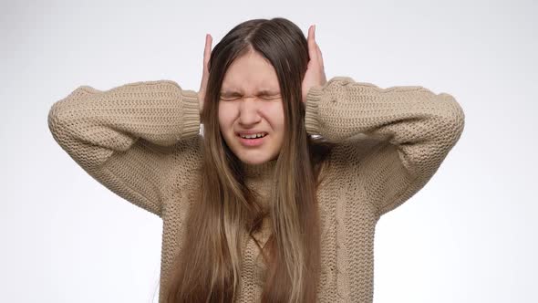 Annoyed Girl of Loud Noise Closing Her Ears with Hands Over White Studio Background