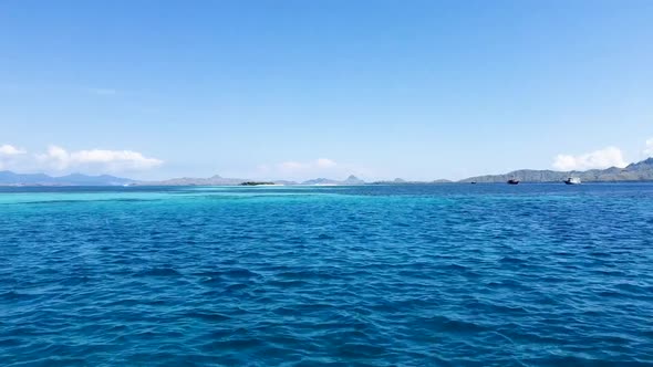 Turquoise water between Komodo and Padar Islands, Indonesia with ships stationed right, Aerial dolly