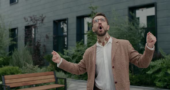 Happy Guy in Glasses and Neckerchief Singing and Dancing While Walking at City Street