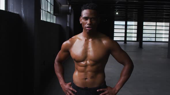 Shirtless african american man flexing his muscles in an empty urban building