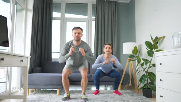 Caucasian Couple is Doing Squats and Kicks at Home in Cozy Bright Room Slow Motion