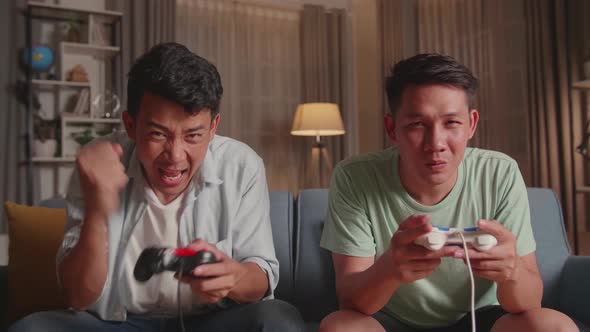 Asian Friends Playing Video Games At Home. Male Happy To Win And Another Man Feeling Disappointed