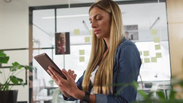 Portrait of caucasian businesswoman using tablet smiling to camera in office