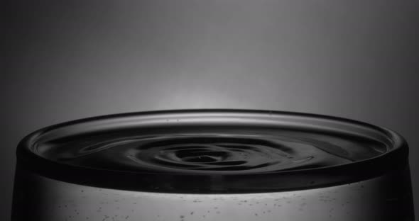 A Drop of Water Drips Into a Full Glass of Water