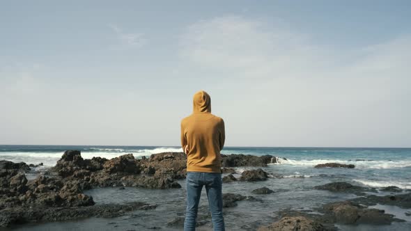 Tourist Man in Yellow Sweatshirt Walks on Volcanic Beach in North of Canary Island Tenerife