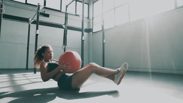 Young woman doing core training with gym ball