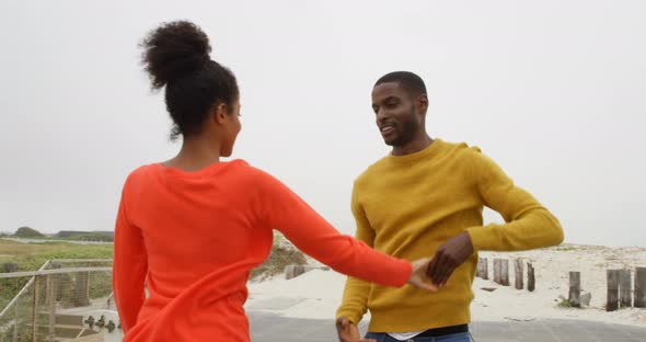 Young romantic black couple dancing together on promenade at beach on a sunny day 4k