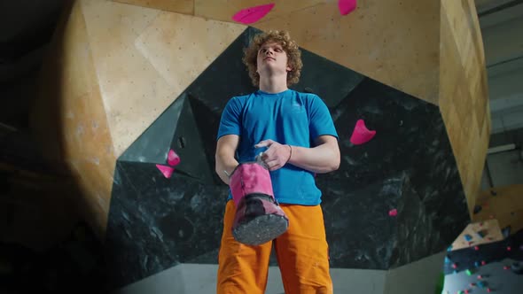 Portrait of a Young Man Climber Guy Stands Against the Background of a Climbing Wall and Use