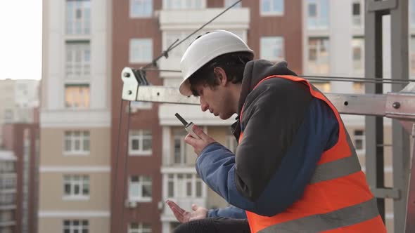 The foreman at the construction site controls the process using a walkie-talkie.