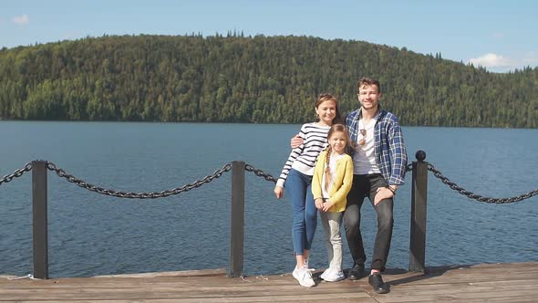 Happy Family with Daughter Fishing in Pond in Fall