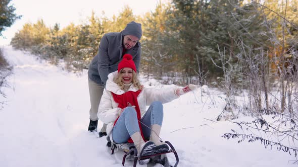 Happy Playful Family Couple Sledding in Winter Park Laughing and Having Fun Together Positive Woman