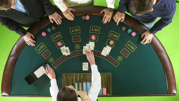 Men Playing Poker at the Table, the Dealer Deals the Cards and the Chips. Green Screen. Top View