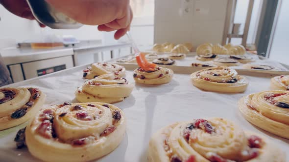 Baker Smears Raw Berry Escargot Buns with Egg Yolk Before Baking