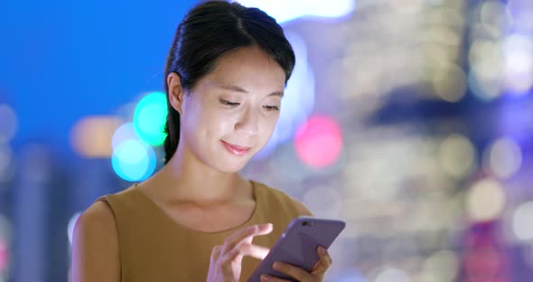 Asian woman check on cellphone in city at night
