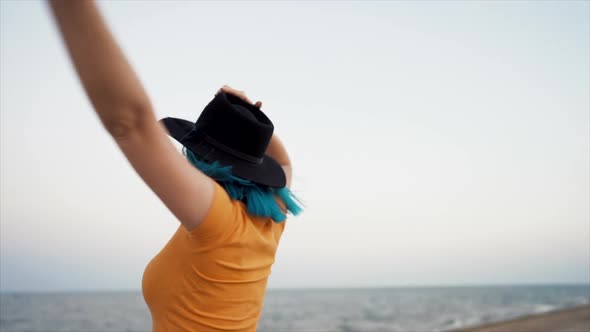 Carefree Unusual Woman with Blue Dyed Hair Dancing, Spinning Around on Sea Background. Femininity