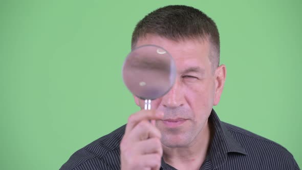 Face of Macho Mature Businessman As Detective Inspecting with Magnifying Glass