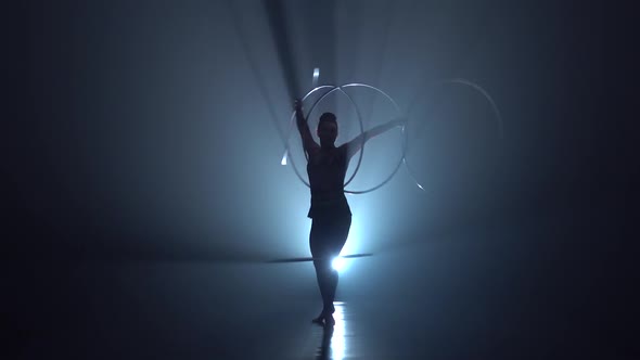 Gymnast Tricks with Hoops on Her Hands and Lifts Her Leg in the Air