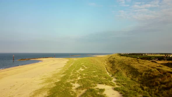 Aerial flyover of an empty golden beach and ocean in Norfolk, England