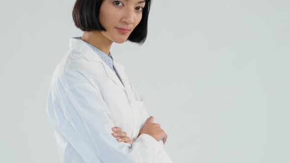 Female doctor standing with arms crossed against white background 4K