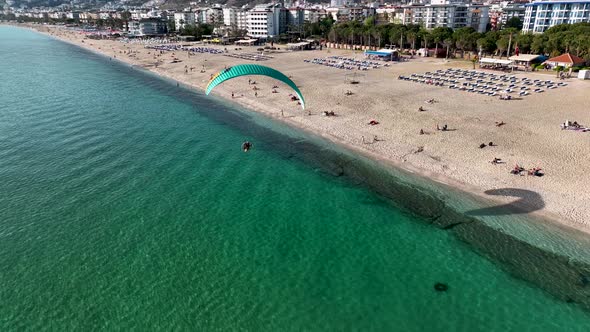 Aerial drone view of parachute jumper flying over beautiful beach