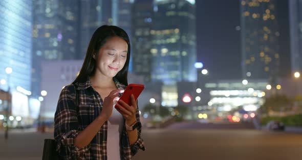 Woman use of mobile phone online in city at night