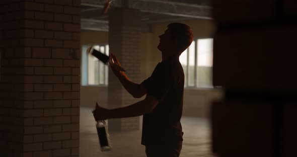 Silhouette of Professional Bartender Juggles Bottles