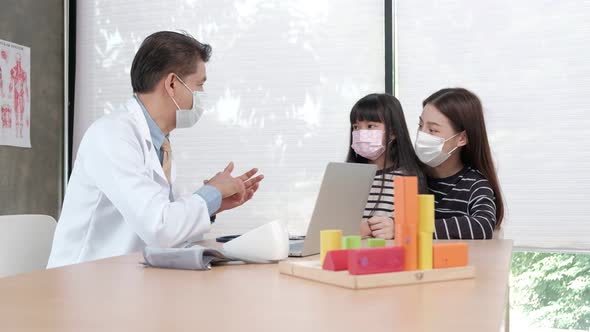 A mother and daughter exam appointment with an Asian male doctor.