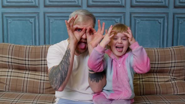 Father and Child Daughter Kid in Pajamas Fooling Sit on Couch in Living Room Smile Look at Camera