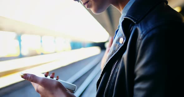 Woman using mobile phone in railway station 4k