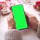 Woman holding smartphone with vertical green screen on Christmas background with gifts. - VideoHive Item for Sale