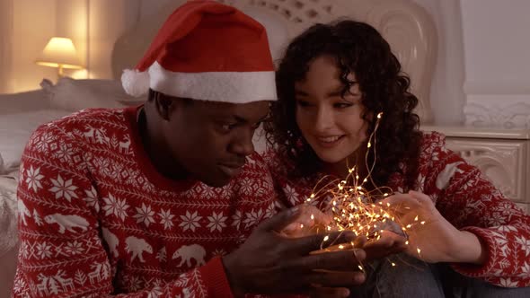 Young Couple in Love Arranging the Christmas Lights and Having Fun in Their Living Room in Christmas
