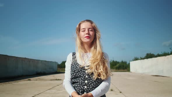 A Young Girl in a Beautiful Dress is Standing Near Concrete Walls and a Field